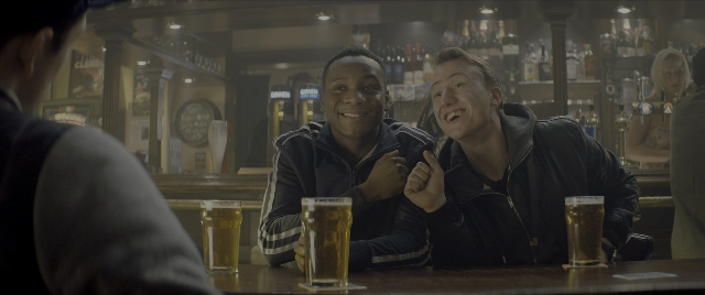 Wide shot frame from Kingsman: The Secret Service — sitting, beer, clock