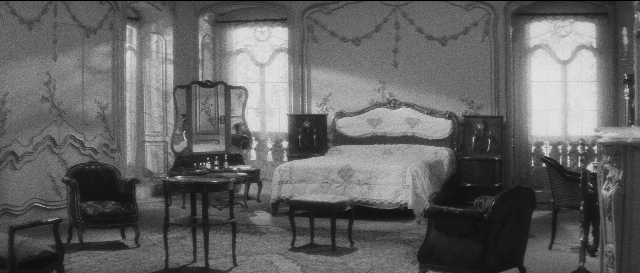 Wide shot frame from L'année dernière à Marienbad — room, table, bed