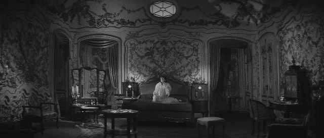 Wide shot frame from L'année dernière à Marienbad — room, table, bed