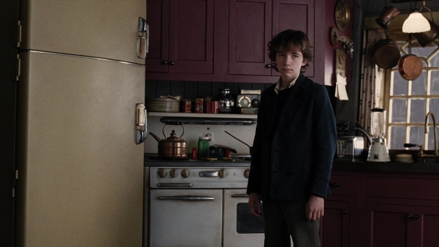 Wide shot frame from A Series of Unfortunate Events — standing, kitchen, coat