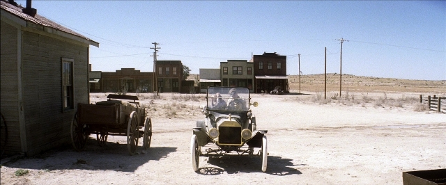 Wide shot frame from There Will Be Blood — street, car, house