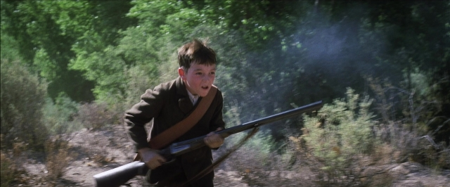 Wide shot frame from There Will Be Blood — standing, gun, face