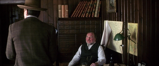 Wide shot frame from There Will Be Blood — sitting, room, hat