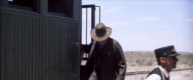 Frame from There Will Be Blood — standing, door, hat