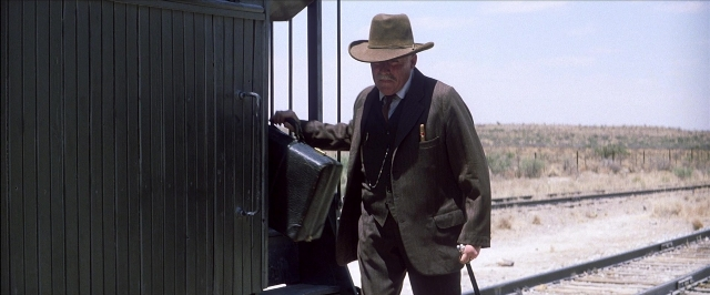 Wide shot frame from There Will Be Blood — standing, hat, car