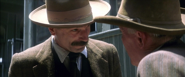 Frame from There Will Be Blood — standing, hat, suit