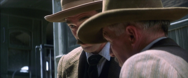 Frame from There Will Be Blood — standing, door, hat