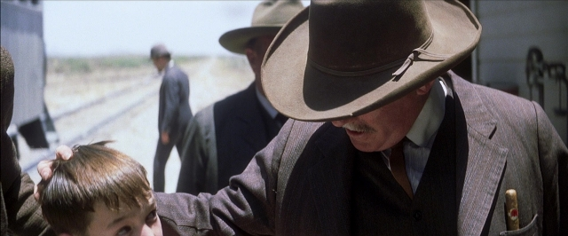 Wide shot frame from There Will Be Blood — standing, hat, suit