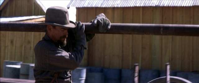 Wide shot frame from There Will Be Blood — standing, hat, shirt
