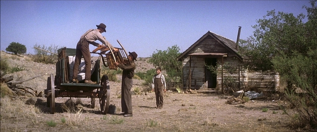 Wide shot frame from There Will Be Blood — sitting, standing, house