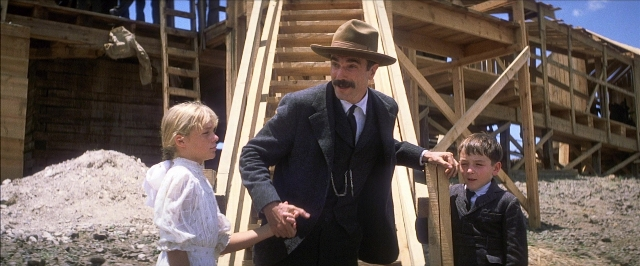 Wide shot frame from There Will Be Blood — standing, hat, suit