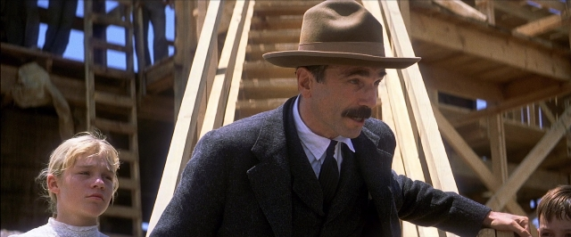 Wide shot frame from There Will Be Blood — standing, hat, suit