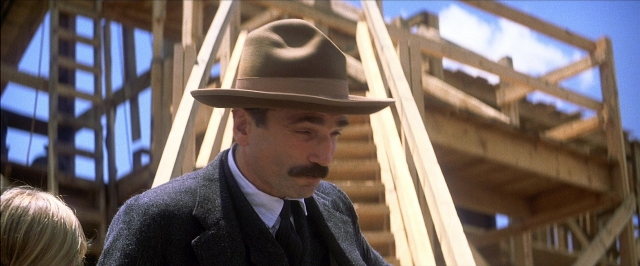 Wide shot frame from There Will Be Blood — standing, hat, suit