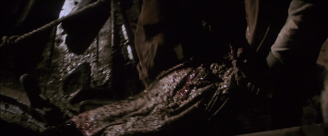 Wide shot frame from There Will Be Blood — animal, hand, knife