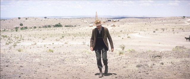 Wide shot frame from There Will Be Blood — walking, hat, suit