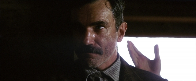 Close-up frame from There Will Be Blood — hand, suit, tie