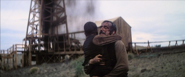 Wide shot frame from There Will Be Blood — standing, hat, beard