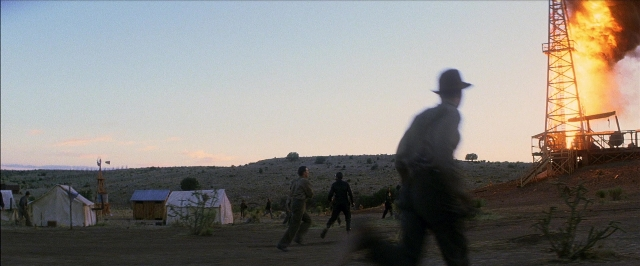 Wide shot frame from There Will Be Blood — walking, hat, fire