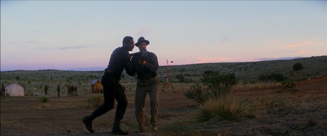Wide shot frame from There Will Be Blood — standing, street, hat