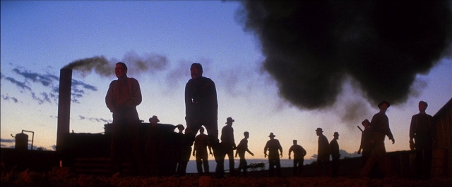 Wide shot frame from There Will Be Blood — standing, smoke, person