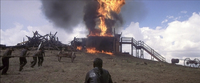 Frame from There Will Be Blood — walking, fire, smoke