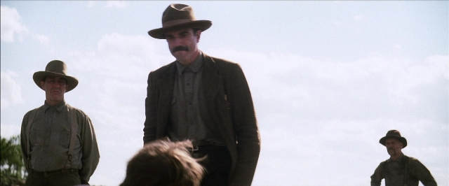 Frame from There Will Be Blood — standing, hat, suit