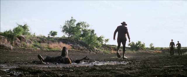 Wide shot frame from There Will Be Blood — walking, street, hat