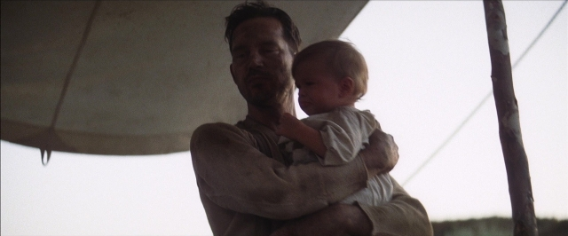 Wide shot frame from There Will Be Blood — standing, shirt, beard