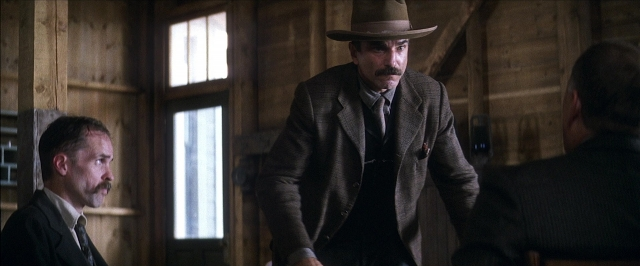 Wide shot frame from There Will Be Blood — sitting, standing, room