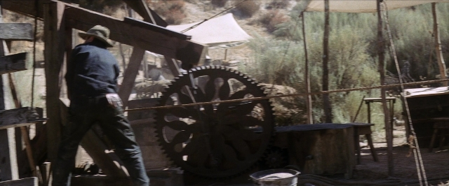 Wide shot frame from There Will Be Blood — standing, hat, coat