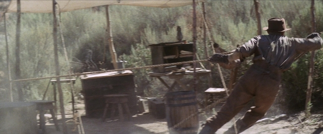 Wide shot frame from There Will Be Blood — standing, table, hat