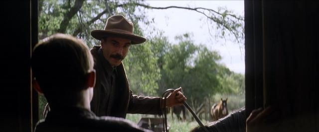 Wide shot frame from There Will Be Blood — standing, hat, coat