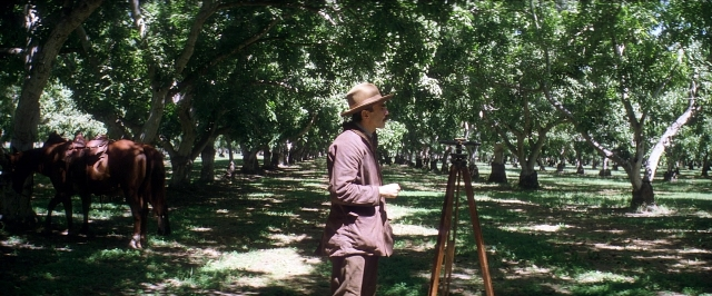 Wide shot frame from There Will Be Blood — book, standing, hat