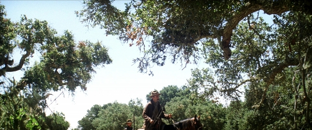 Wide shot frame from There Will Be Blood — sitting, hat, coat