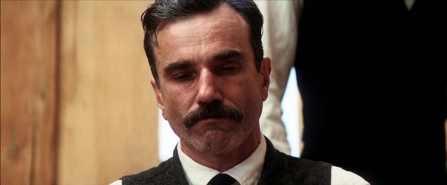 Close-up frame from There Will Be Blood — room, suit, tie