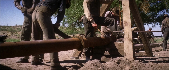 Wide shot frame from There Will Be Blood — standing, pipe, person