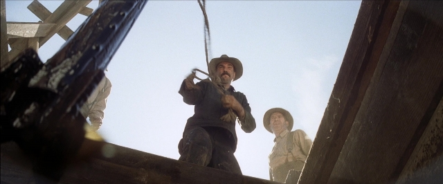 Wide shot frame from There Will Be Blood — standing, dialogue, hat