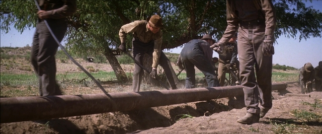 Wide shot frame from There Will Be Blood — standing, pipe, person