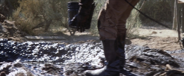 Wide shot frame from There Will Be Blood — standing, hand, bag
