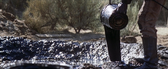 Wide shot frame from There Will Be Blood — standing, person, car tire