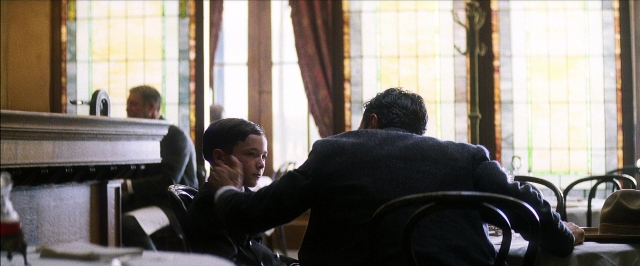 Wide shot frame from There Will Be Blood — sitting, table, hat