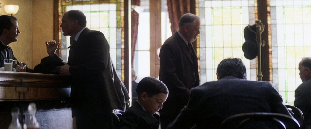 Wide shot frame from There Will Be Blood — sitting, standing, table