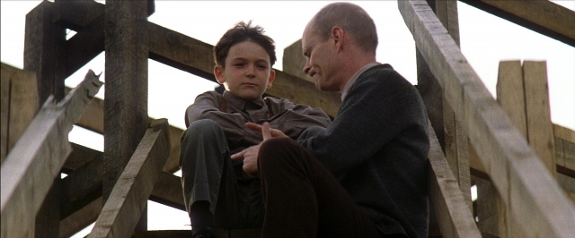 Wide shot frame from There Will Be Blood — sitting, dialogue, suit