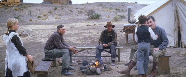 Wide shot frame from There Will Be Blood — sitting, hat, dress