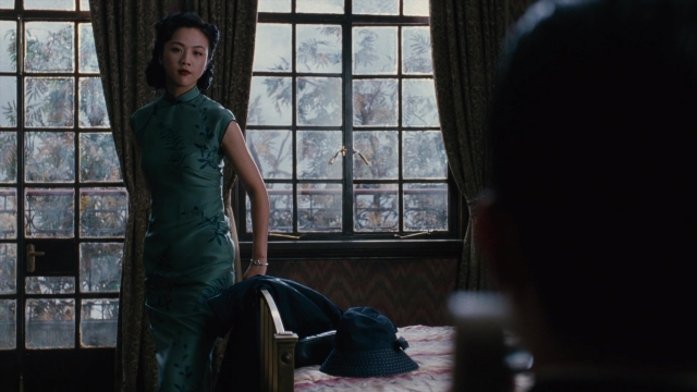 Wide shot frame from Se, jie — standing, room, hat