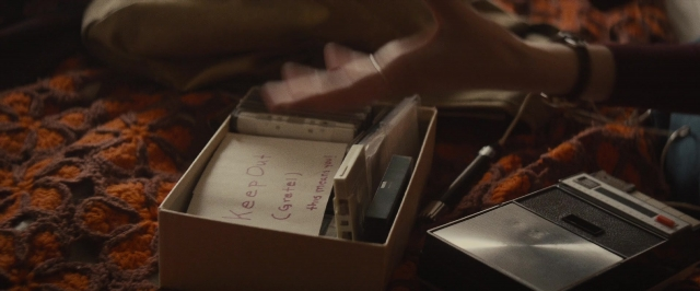 Wide shot frame from The Diary of a Teenage Girl — sitting, bed, hand