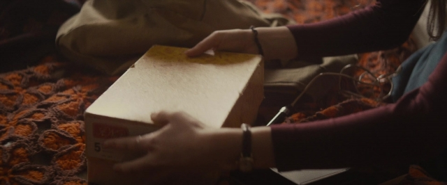 Wide shot frame from The Diary of a Teenage Girl — sitting, bed, bag