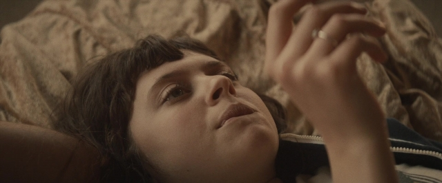 Wide shot frame from The Diary of a Teenage Girl — room, bed, hand