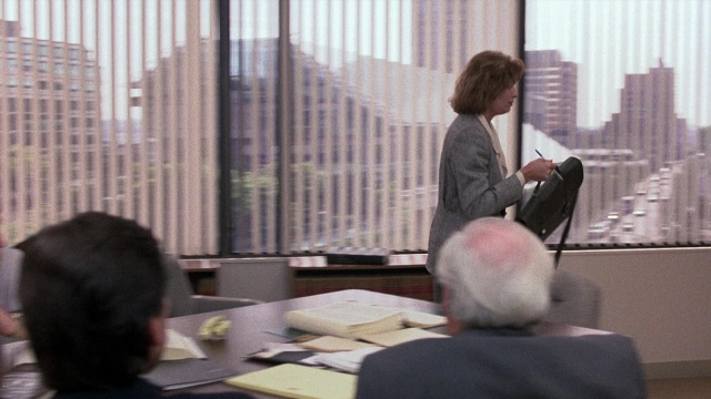 Frame from The Accused — sitting, standing, room