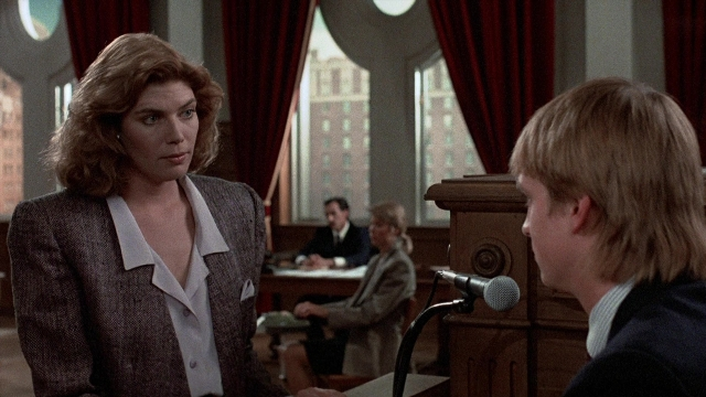 Wide shot frame from The Accused — sitting, standing, suit